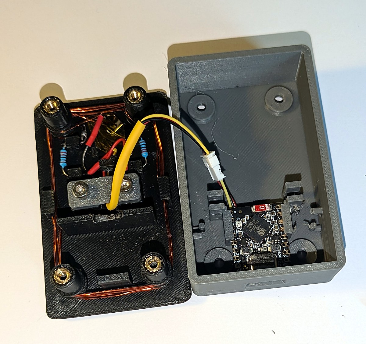 The case open: the lid with both windings and their resistors, the base with the board